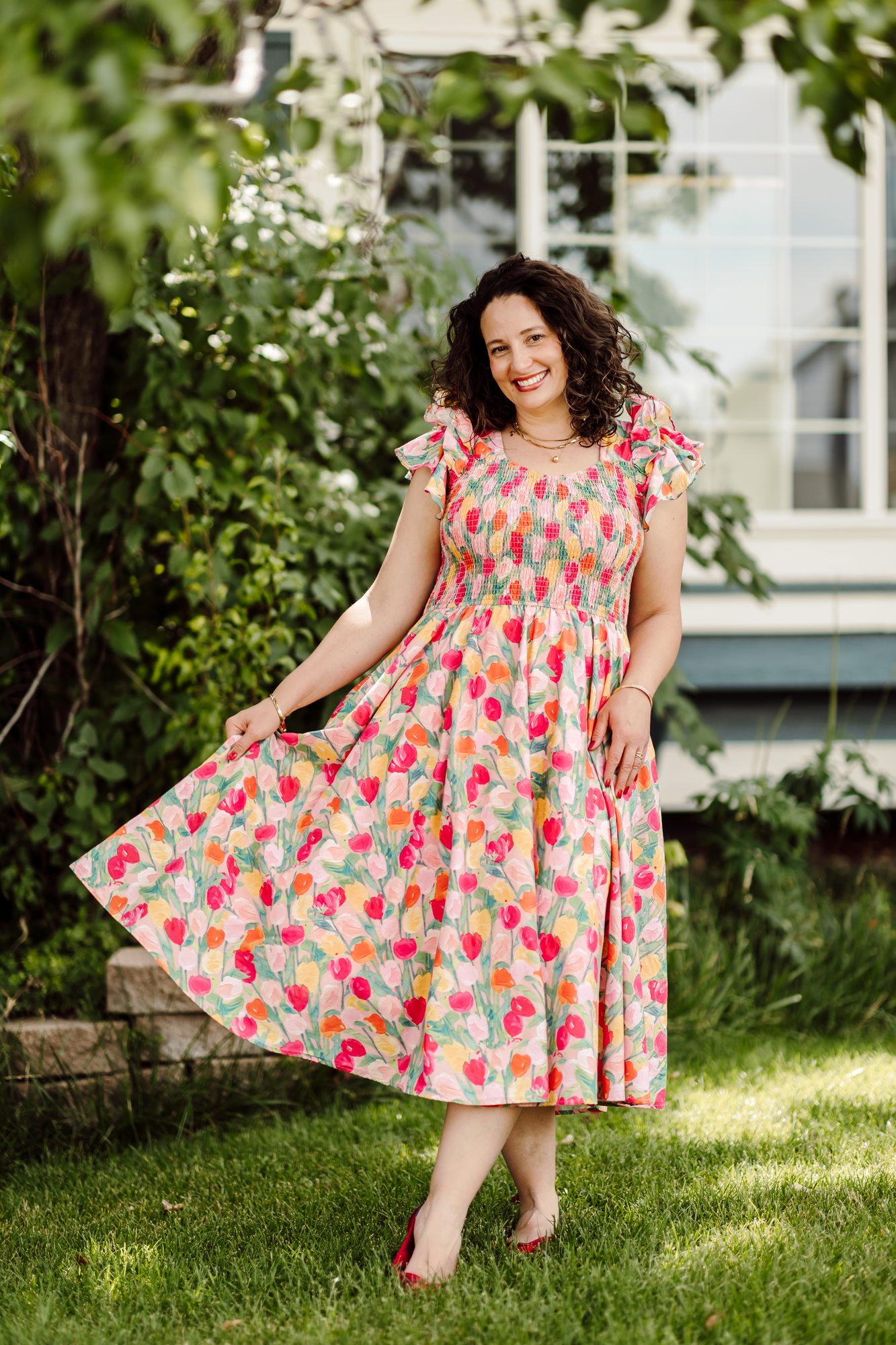 Business owner in a tulip-print dress, fanning out the skirt on a sunny lawn