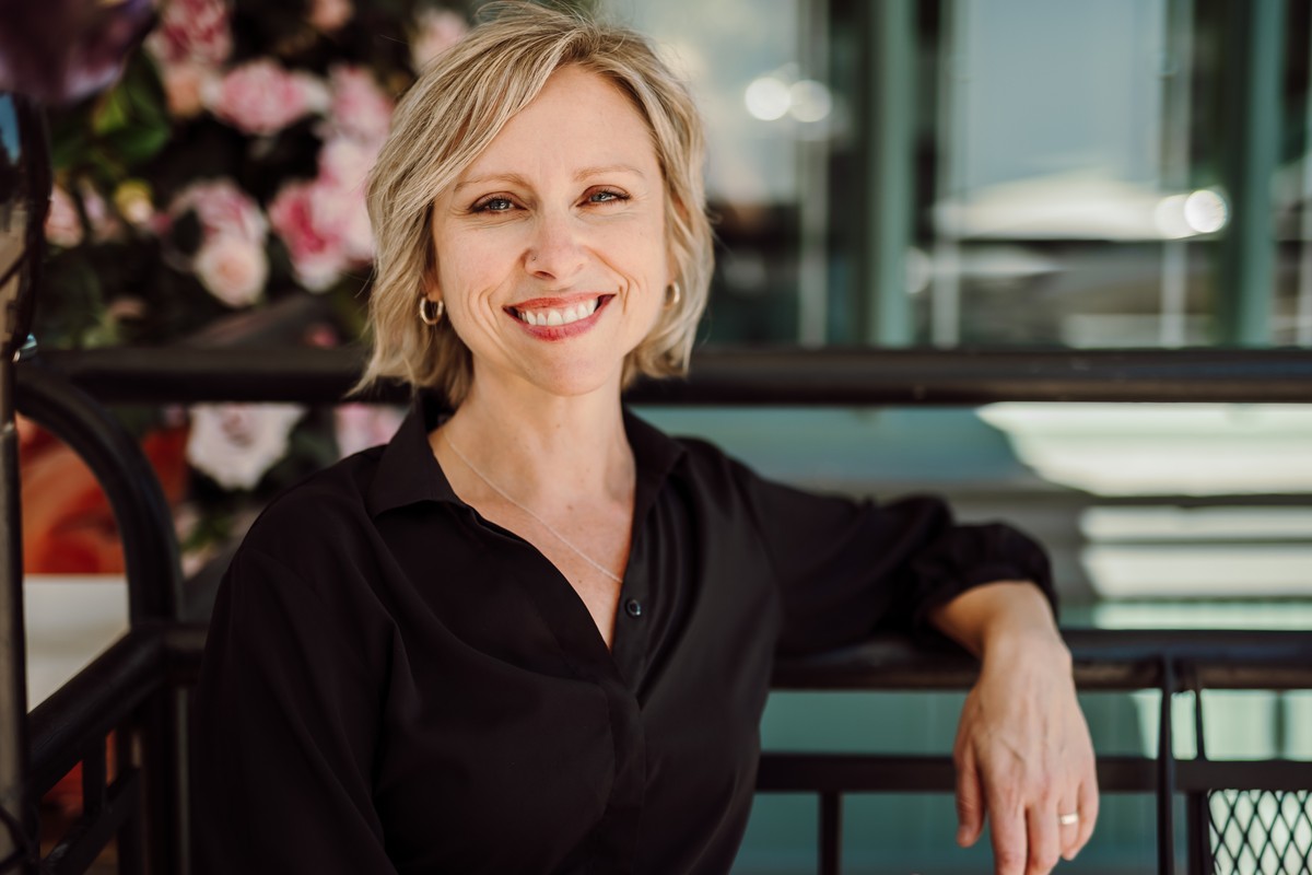 Client in a black button-up shirt, seated beside pink flowers
