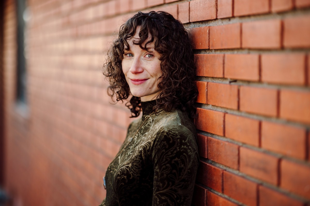 The same client leaning back against a red brick wall, smiling over her shoulder